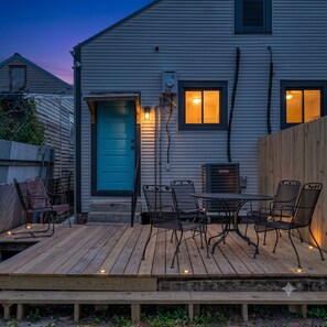 A wooden deck with outdoor furniture, a blue door, and a small porch area. - Charming 2BR Bywater shotgun with private yard. Walk to cafés, near French Quarter. (New Orleans)