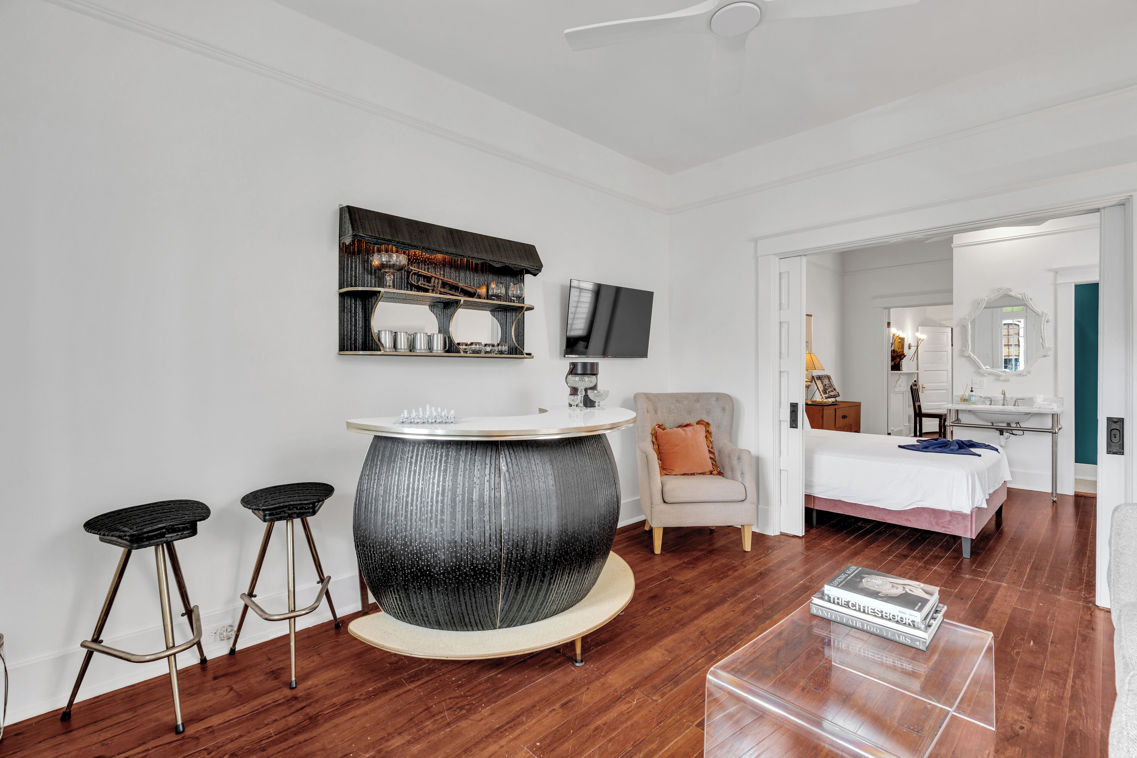 Une chambre moderne avec une table de bar ronde, un lit, une chaise et un téléviseur fixé au mur.