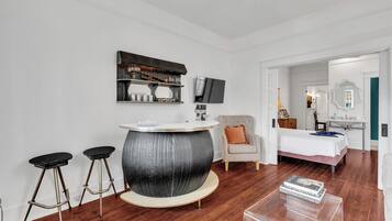 Une chambre moderne avec une table de bar ronde, un lit, une chaise et un téléviseur fixé au mur.