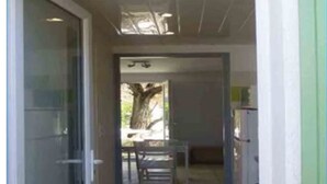 Een gang met een glazen deur aan de linkerzijde, een bank in het midden en een deur aan de rechterkant.