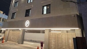 A multi-story building with a parking garage entrance, illuminated by overhead lights. - Groove Hotel (Jeonju)