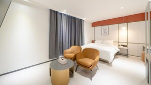 A modern hotel room with a bed, two armchairs, a small table, and a nightstand. - Groove Hotel (Jeonju)