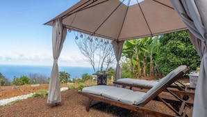 A beachside lounge with a canopy, two reclining chairs, and a table with a bottle. - "El pajal House Relax" by Interhome (Santa Ursula)
