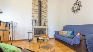A living room with a stone fireplace, a blue sofa, and a wooden dining table. - "El pajal House Relax" by Interhome (Santa Ursula)