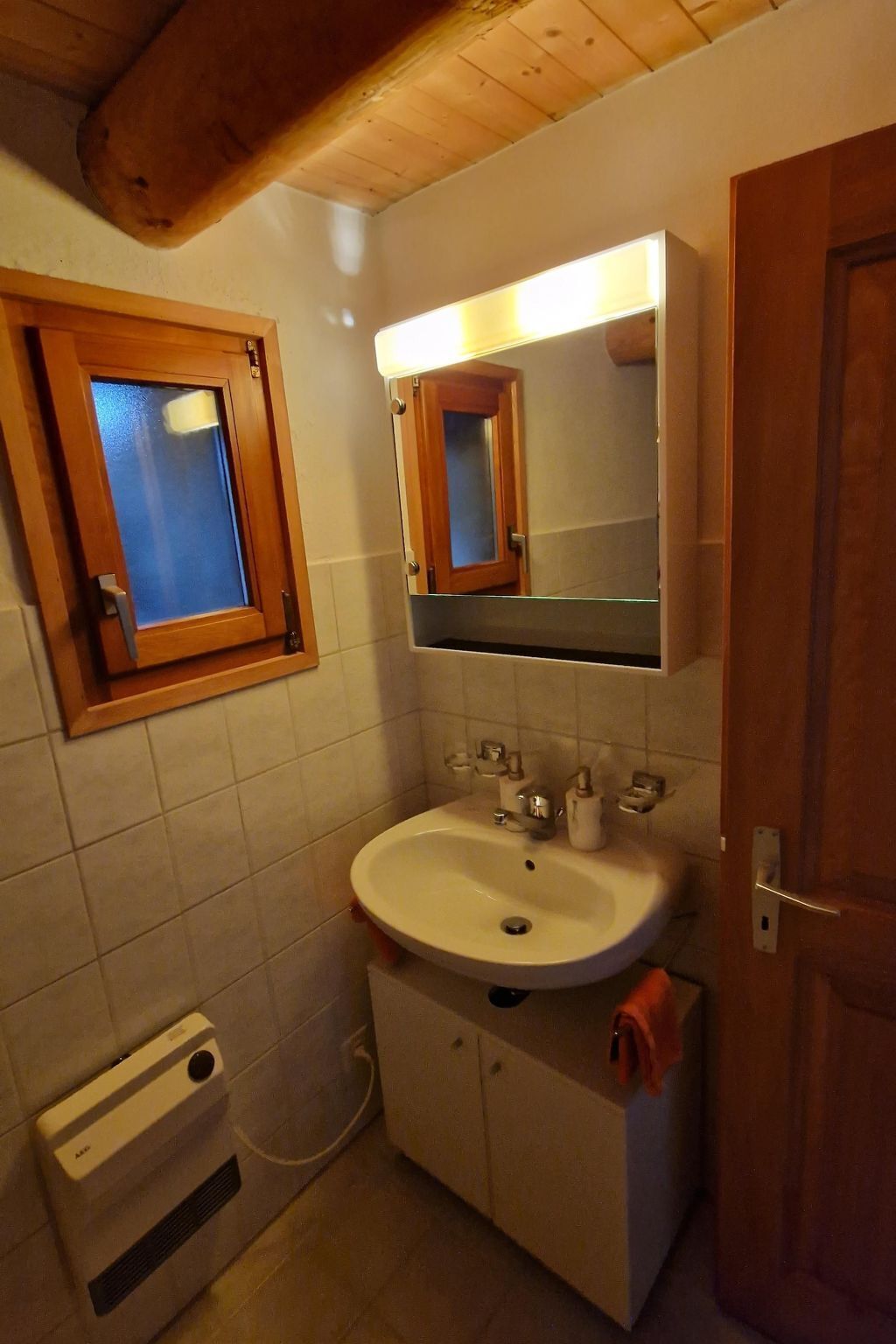 A bathroom with a white sink, a mirror, and a wooden door.