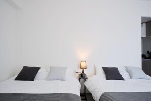 Een hotelkamer met twee bedden, een nachtkastje met een lamp en een witte muur.