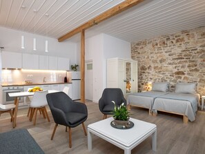 A modern apartment with a kitchen, dining area, and a living room with a stone wall. - Studio mit atemberaubendem Blick auf das Meer by Interhome (Kalami)