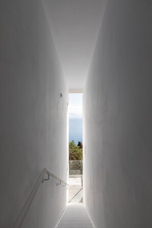 A narrow, white-walled hallway leading to a balcony with a view of the sea. - Luxuriöse Wohnung mit Meerblick Stoa Serenity by Interhome (Kalami)