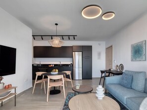 A modern living room with a sofa, coffee table, and dining area. - Luxuriöse Wohnung mit Meerblick Stoa Serenity by Interhome (Kalami)