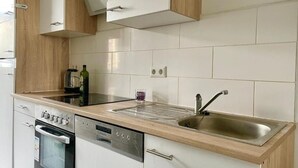 Una cocina moderna con armarios blancos, un lavamanos de acero inoxidable y un horno empotrado.