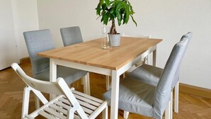 Una mesa de comedor con cuatro sillas, una planta en maceta y una jarra de vidrio transparente.