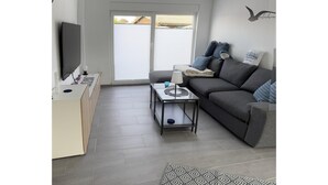 Un salon moderne avec un canapé, une table basse et un téléviseur posé sur un meuble.