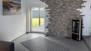 Un salon moderne avec un mur d’accent en pierre, un ventilateur de plafond, un téléviseur fixé au mur et une porte donnant sur l’extérieur.