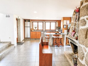 A spacious kitchen with a central island, wooden cabinets, and a stone fireplace. - Casa da Lage by Interhome (Covas)