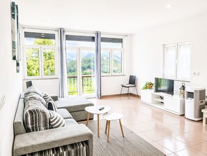 A modern living room with a sofa, a TV, a small table, and a balcony with curtains. - Casa de Casarelhos by Interhome (Covas)