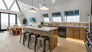Een moderne keuken met een groot schiereiland, barkrukken, hanglampen en een backsplash van natuursteen.