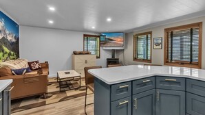 A modern kitchen with a large island, a dining area with a table and chairs, and a cozy seating area with a sofa and a blanket. - Cute Cottage1/2 mile to Village, Hot Tub (Ellicottville)