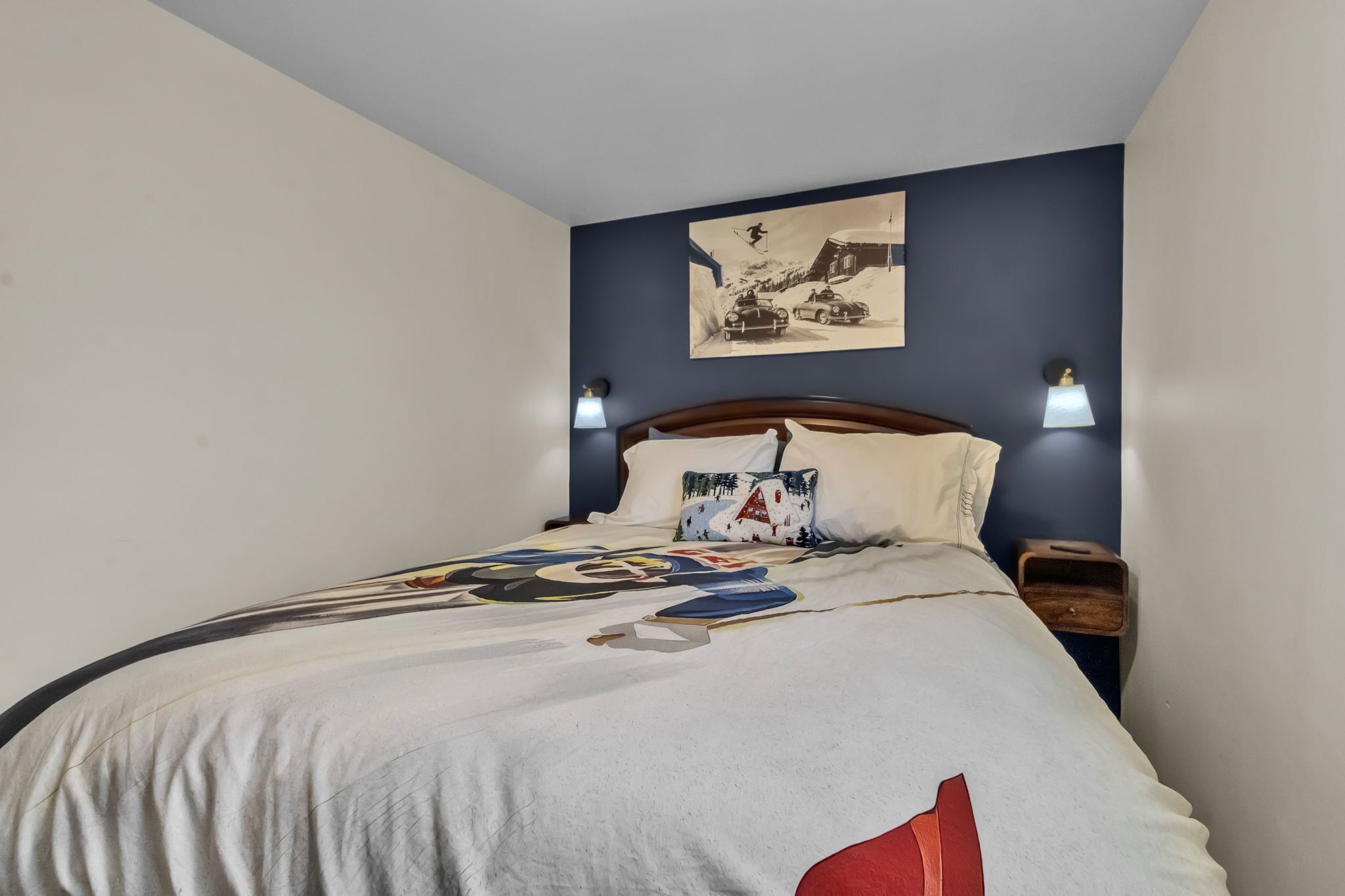 Ein Schlafzimmer mit einem Bett, einem Wandbild, zwei Nachttischlampen und einem Nachttisch.