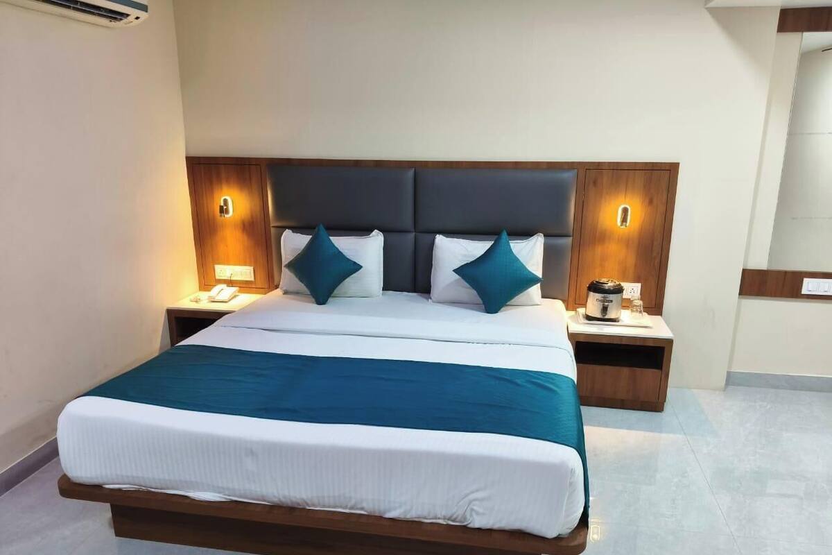 Una cama grande con cabecera de madera, dos mesitas de noche y una mesita auxiliar con lámpara.