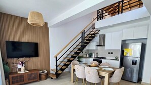 Un soggiorno moderno con zona pranzo, cucina e una scala.