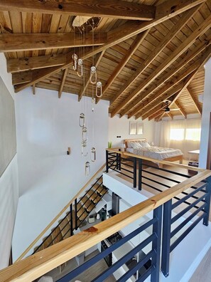 A spacious loft bedroom with a high ceiling, exposed wooden beams, and a modern staircase. - Estrella Garden • Antlia 304 New Modern Penthouse (Dominicus)