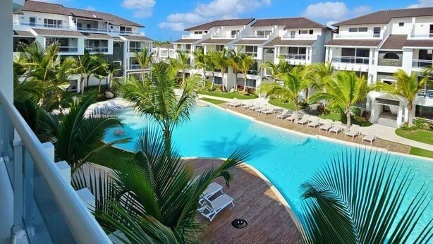 Un resort con piscina circondata da palme e edifici a più piani.