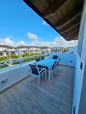 A balcony with a table and chairs, overlooking a residential area with multiple buildings. - Estrella Garden • Antlia 304 New Modern Penthouse (Dominicus)