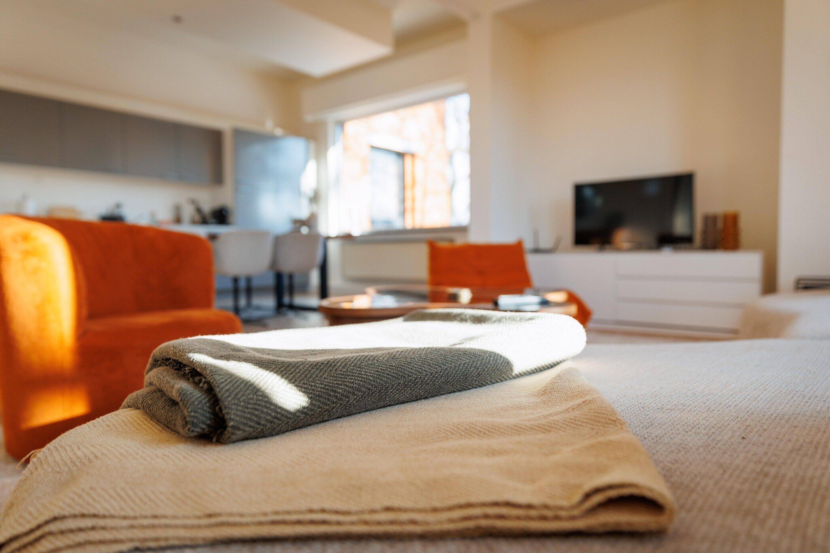 Ein ordentlich eingerichtetes Wohnzimmer mit einer Couch, einem Fernseher und einem Fenster, das für natürliches Licht sorgt.