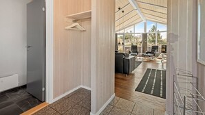 Un interno moderno con soffitto in legno, una porta grigia e un'area salotto con vista.