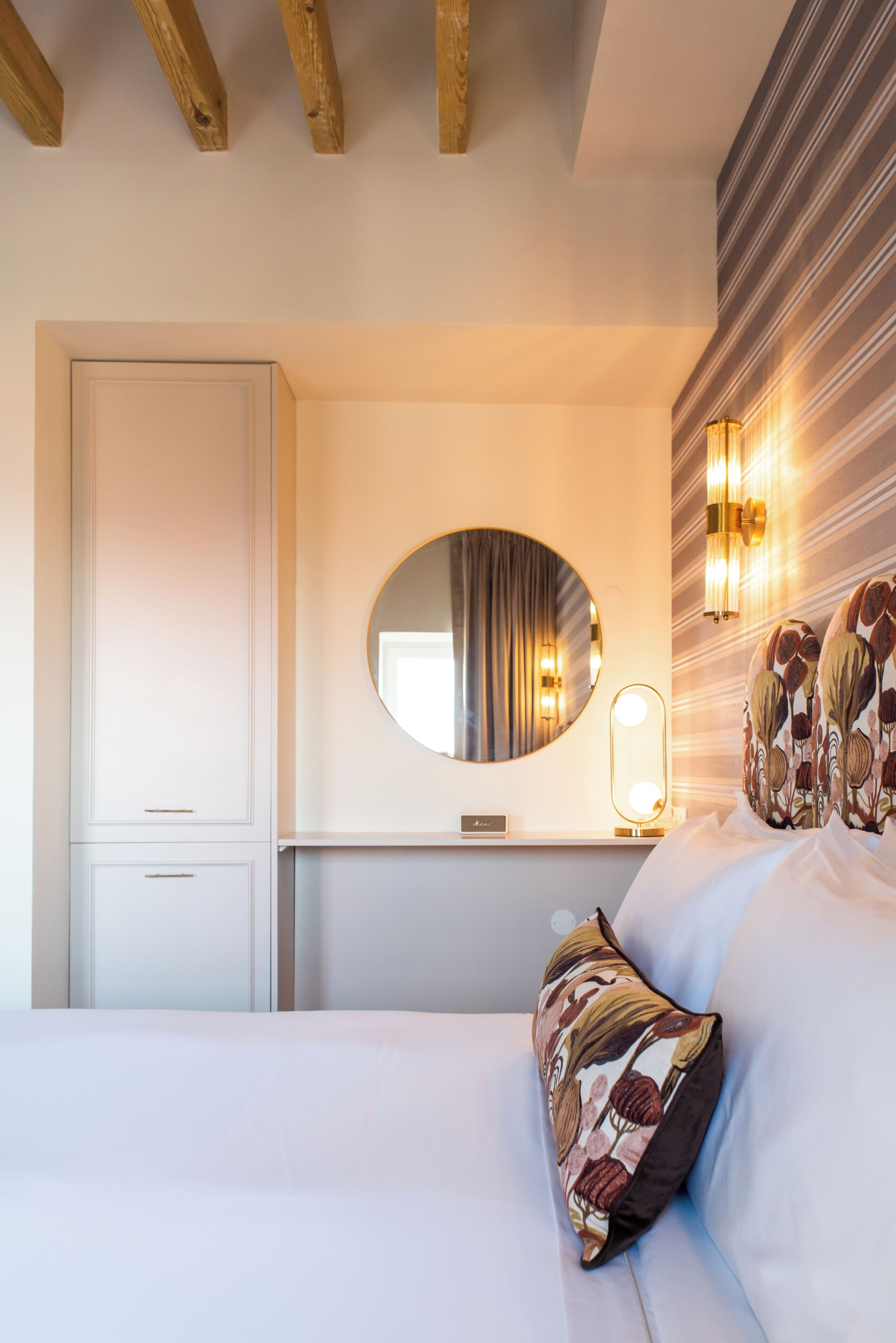 A bedroom with a bed, a bedside table, a mirror, and a wardrobe.