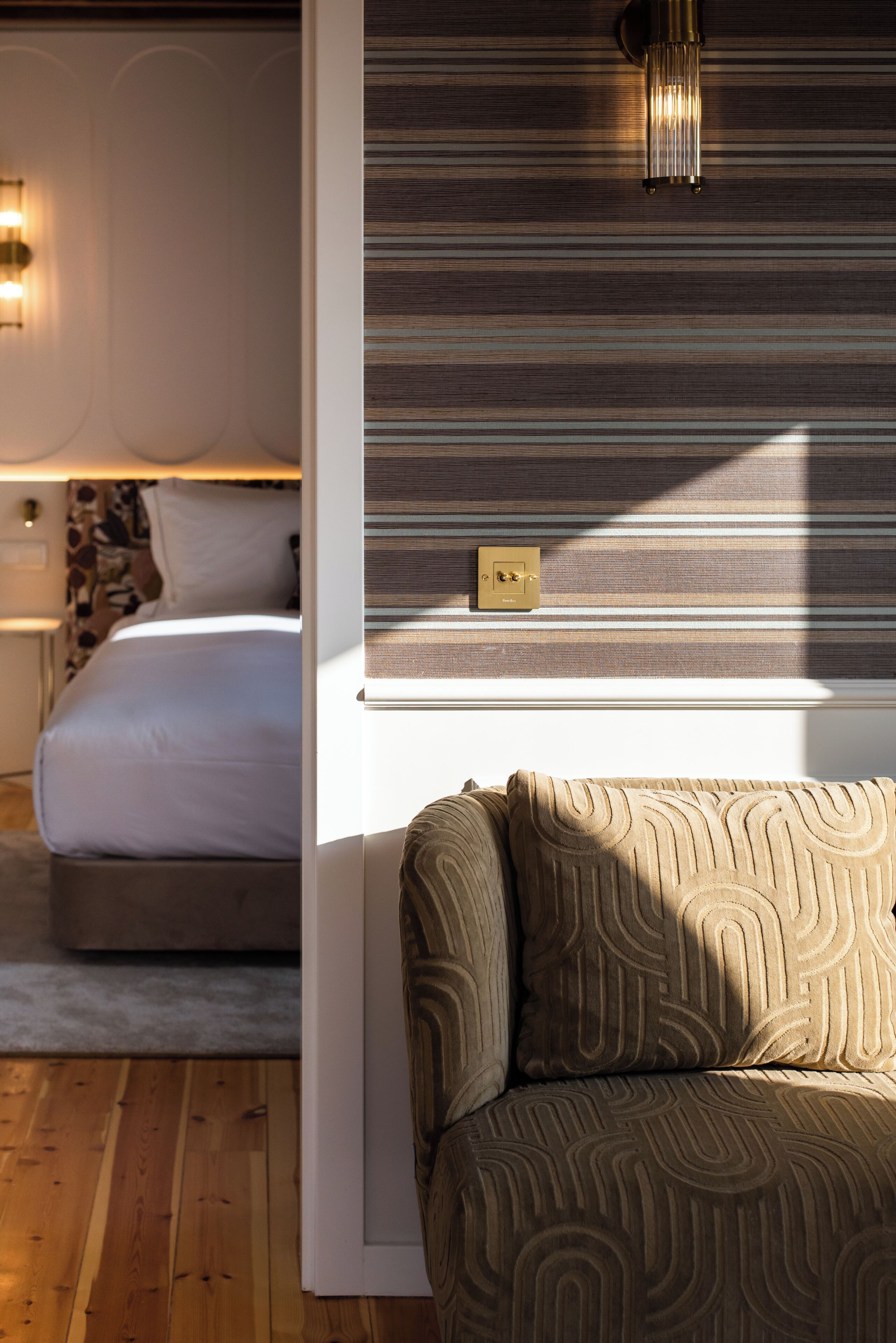 A bedroom with a bed, bedside lamp, and a wall-mounted light fixture.