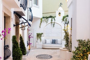 Une ruelle étroite avec un canapé blanc, de la verdure et un mur décoratif.