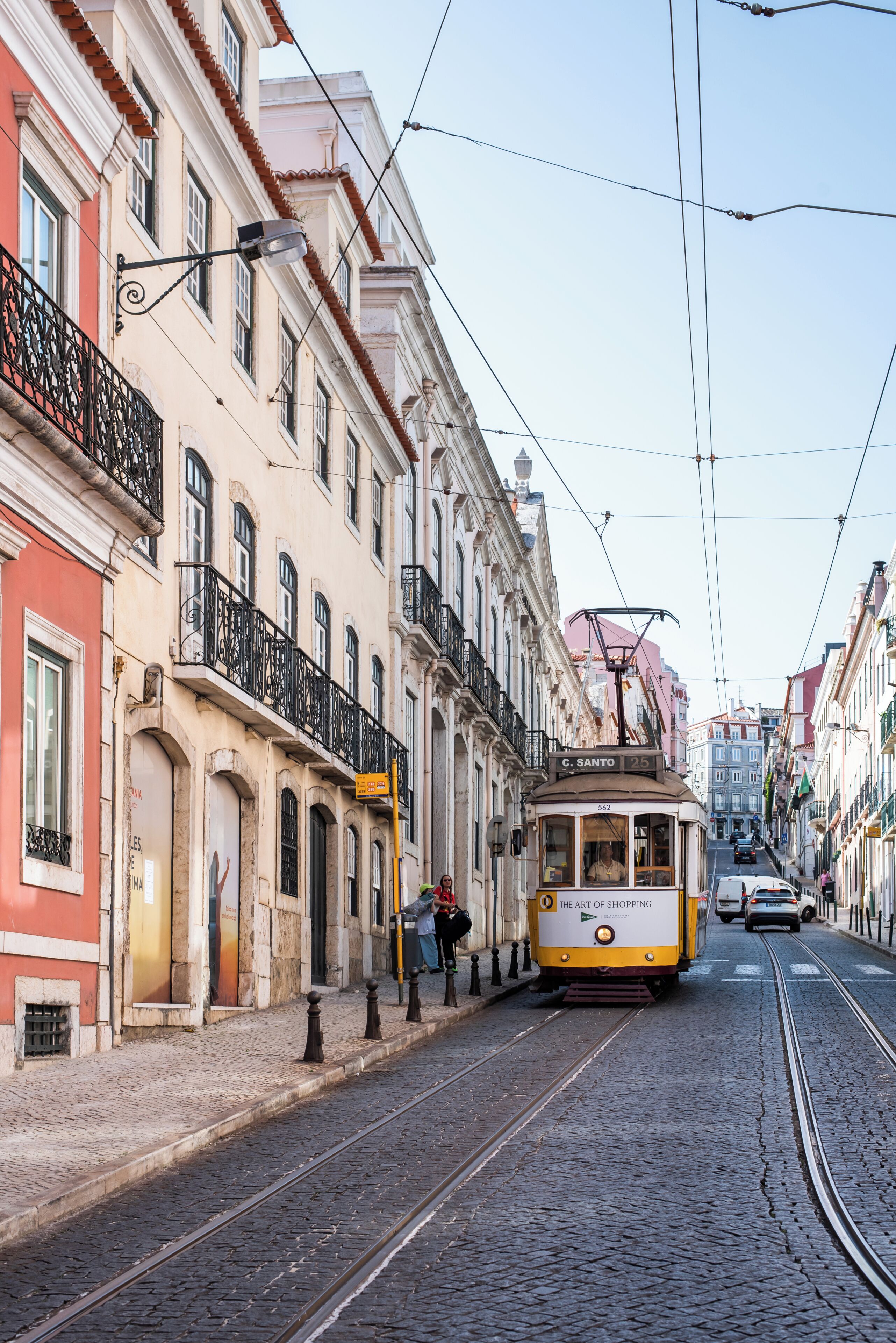 Um eléctrico numa rua de calçada, com edifícios de ambos os lados.