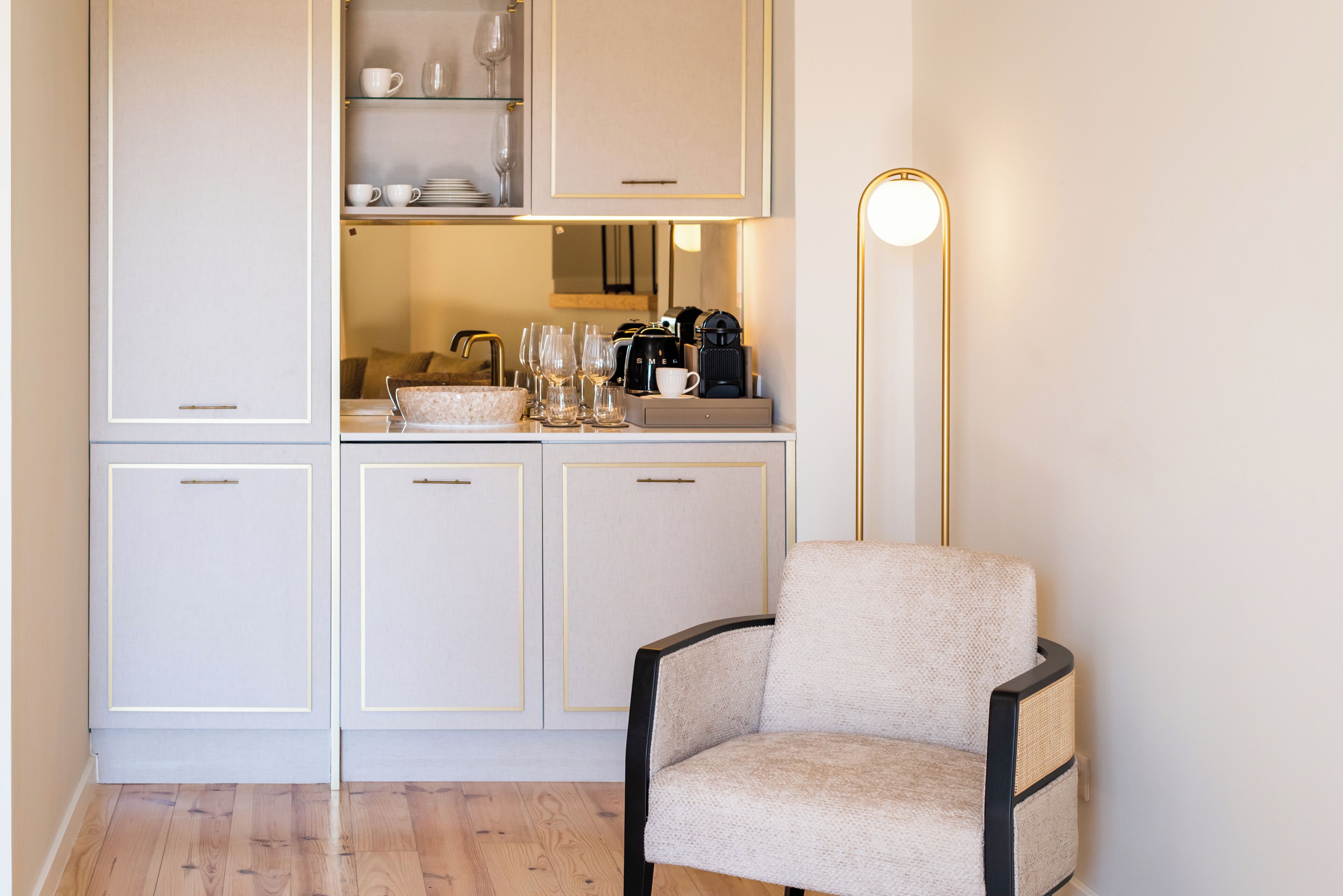 Een kitchenette met kastjes, een koffiezetapparaat en een stoel.