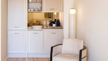 Een kitchenette met kastjes, een koffiezetapparaat en een stoel.