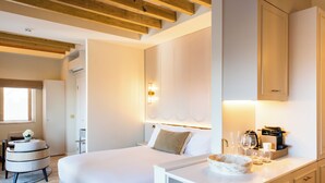 A bedroom with a bed, bedside table, lamp, and a view of the bathroom.