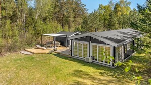 A modern cabin with a deck, large windows, and a covered outdoor seating area. - "Landrich" -  from the sea by Interhome (Hadsund)