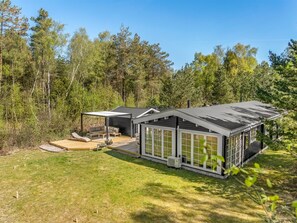 A modern cabin with a deck, large windows, and a covered outdoor seating area. - "Landrich" -  from the sea by Interhome (Hadsund)