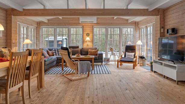 A spacious living area with wooden floors, large windows, a sofa set, a dining table, and a TV. - "Landrich" -  from the sea by Interhome (Hadsund)