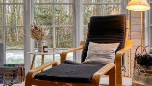 A cozy room with a large window, a comfortable chair, a small table with a vase, and a lamp. - "Landrich" -  from the sea by Interhome (Hadsund)