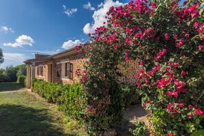 A building with a stone facade and a garden with pink flowers. - Son Sea Villa – 5 minutes from Es Trenc, private villa and total tranquillity (Campos)