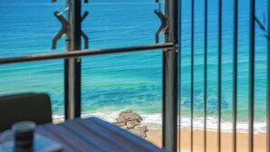A view of the ocean through metal bars, a wooden table, and a chair. - Elite Escape - Absolute Beachfront Luxury (Newcastle)