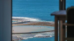 A view of a coastal area with a beach, rocky shoreline, and a pier. - Elite Escape - Absolute Beachfront Luxury (Newcastle)