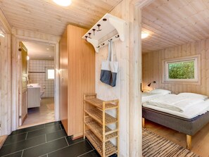 A wooden interior with a bed, a shelf, a hanging bag, and a window with a view. - "Yorick" - 350m to the fjord by Interhome (Tarm)