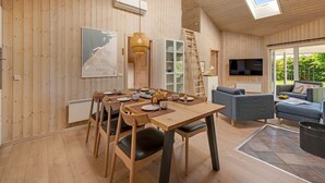 Un interno in legno con un tavolo da pranzo, sedie, un divano, una TV e una mappa appesa al muro.