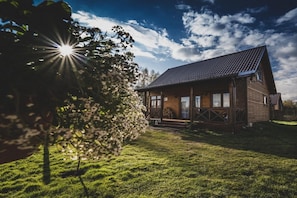 Une cabane en bois avec un toit en pente, une véranda et une pelouse bien entretenue.