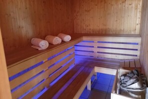 A sauna room with wooden benches and a bench with towels. - Holiday Home With Sauna, Jacuzzi and Private Pond (Lipusz)