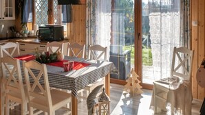 A dining area with a checkered tablecloth, white chairs, a small Christmas tree, and a lantern on the floor. - Holiday Home With Sauna, Jacuzzi and Private Pond (Lipusz)
