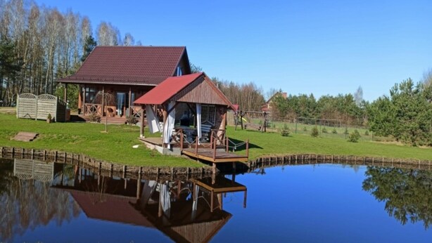 A lakeside cabin with a dock extending into the water, surrounded by a grassy area and trees. - Holiday Home With Sauna, Jacuzzi and Private Pond (Lipusz)