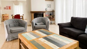 A living room with two grey armchairs, a black sofa, and a wooden coffee table with a patchwork design.